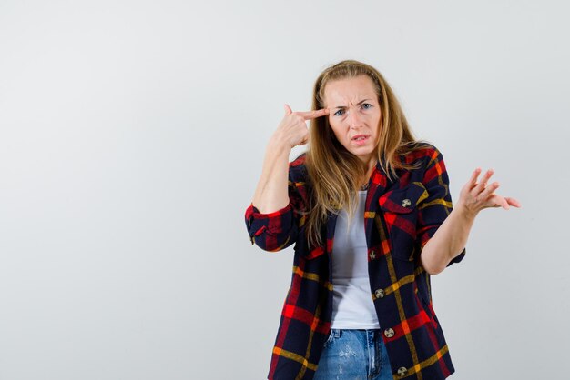 Young woman holding her finger to her head on white background