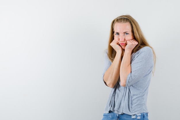 Young woman holding her fists on her cheeks on white background