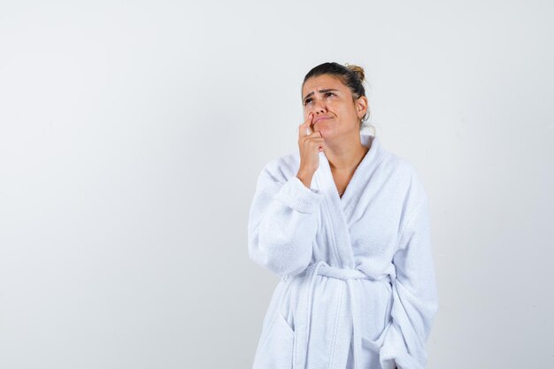 Young woman holding index finger near mouth while thinking