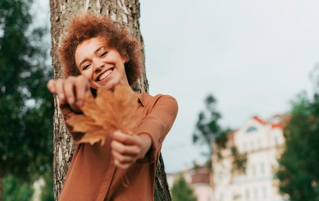 Free photo young woman holding a leaf with copy space