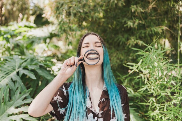 Young woman holding magnifying glass in front of her mouth