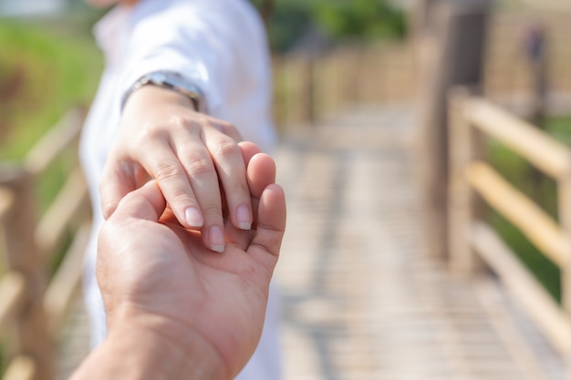 無料写真 花の庭で彼を導きながら男の手を握る若い女性