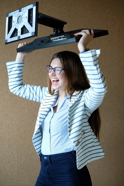 Young woman holding monitor screen with rage