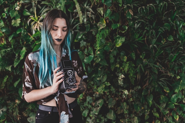 Young woman holding old retro styled camera in hand