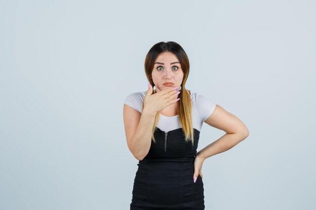 Giovane donna che tiene una mano sul mento e sembra scioccata