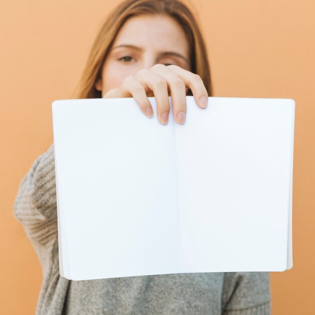 Young woman holding an open white book in front of camera