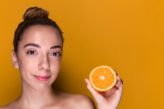 Молодая женщина, держащая ломтик апельсина