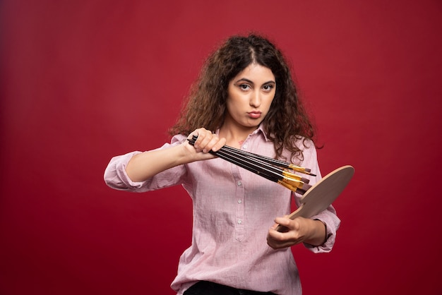 Young woman holding paint brushes and paint palette .