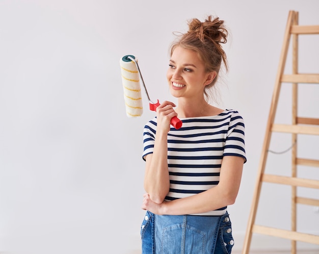 Foto gratuita giovane donna con in mano un rullo di vernice