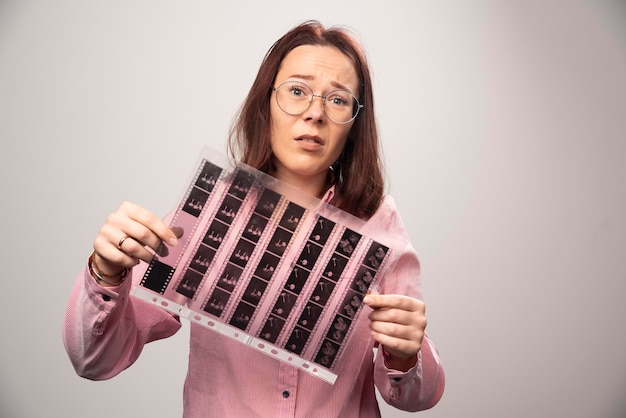 Free photo young woman holding a photo tape on a white . high quality photo