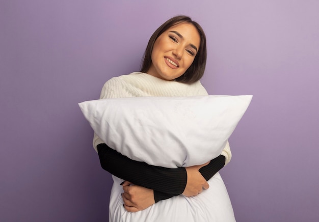 Young woman holding pillow happy and positive 