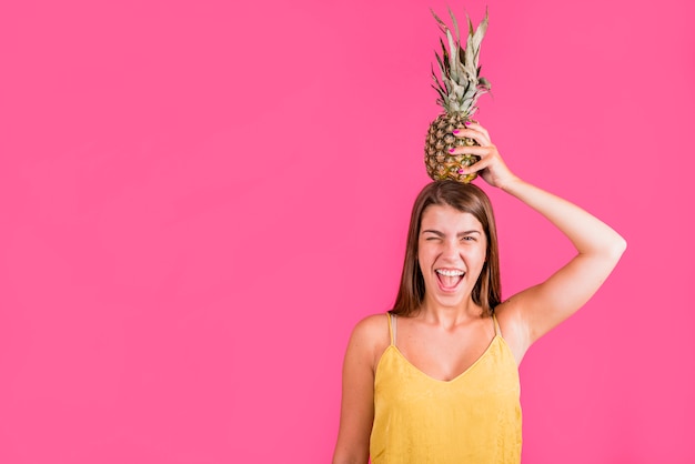 Young woman holding pineapple on head