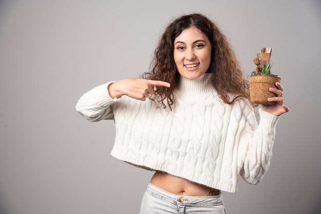 Young woman holding a plant and pointing it. High quality photo