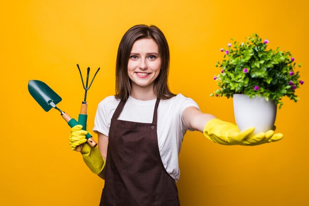 Young woman holding a plant and tools isolated