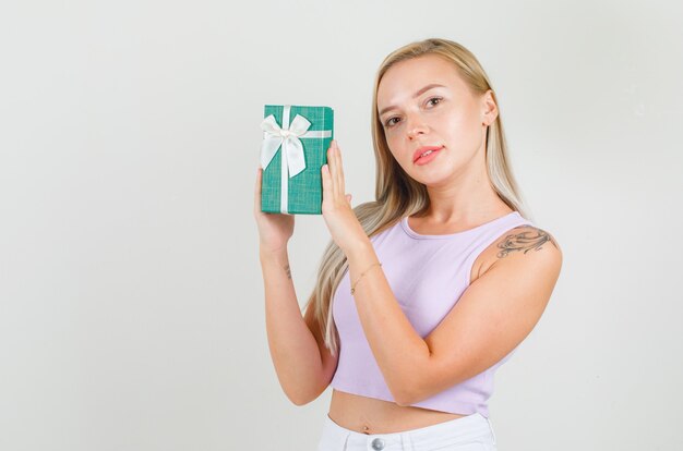 Young woman holding present box in singlet