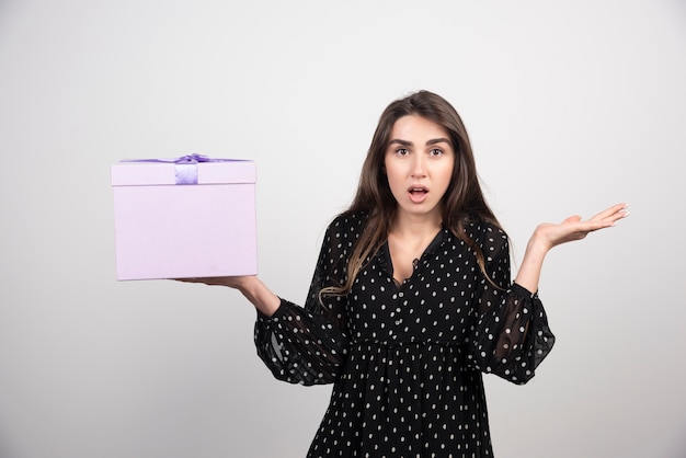 Молодая женщина, держащая фиолетовую подарочную коробку