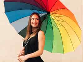 Free photo young woman holding a rainbow umbrella