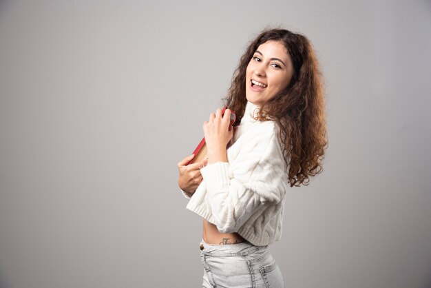 Young woman holding red book on a gray wall. High quality photo