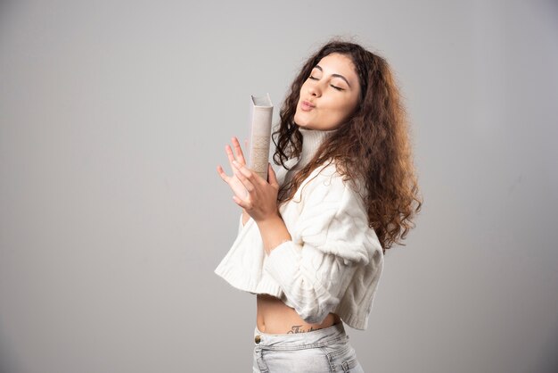 Young woman holding red book on a gray wall. High quality photo