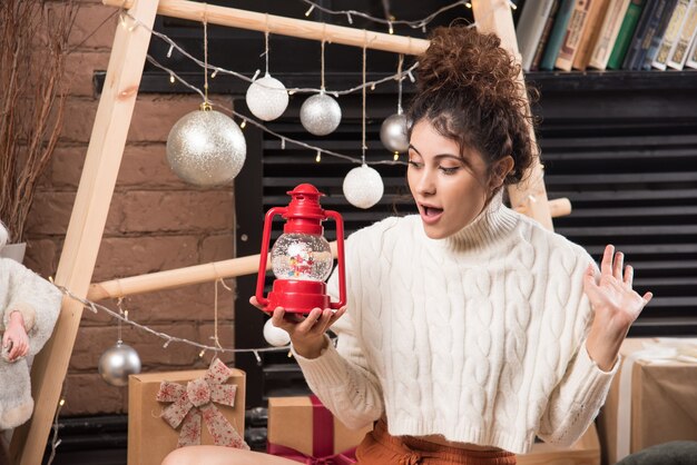 Young woman holding a red Christmas lamp 