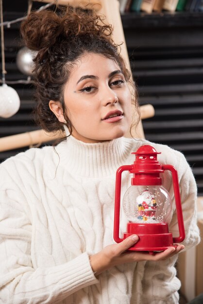 Young woman holding a red Christmas lamp 