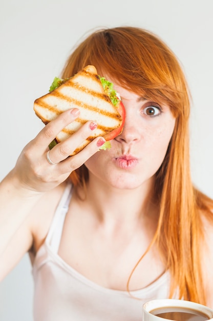 Free photo young woman holding sandwich in front of her eyes