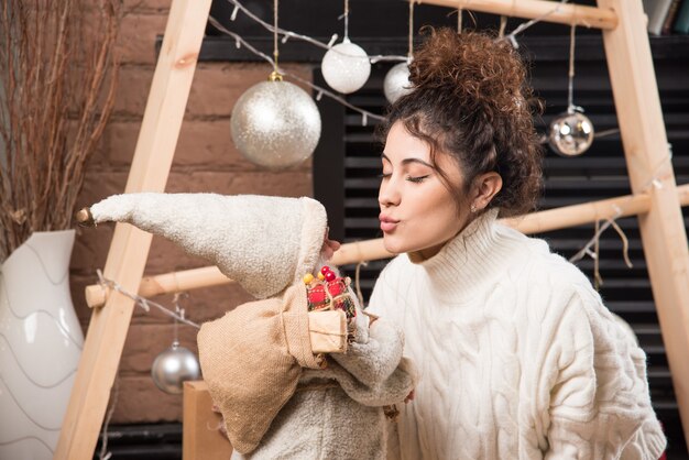 Free photo young woman holding a santa claus toy