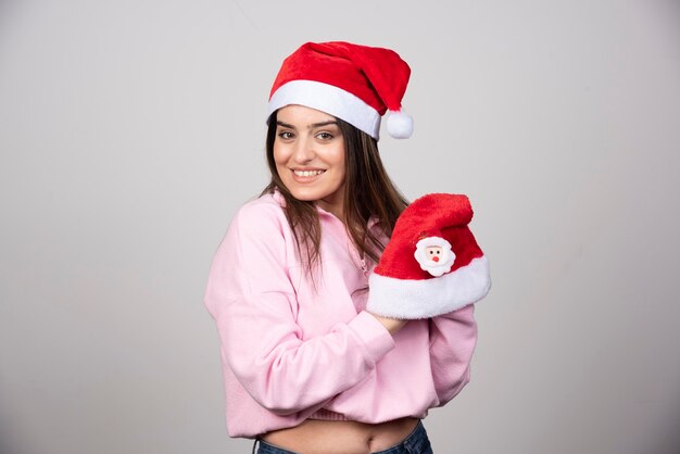 A young woman holding Santa's hats and posing.