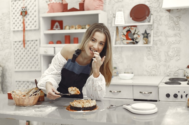 Young woman holding self-made cake in the kitchen