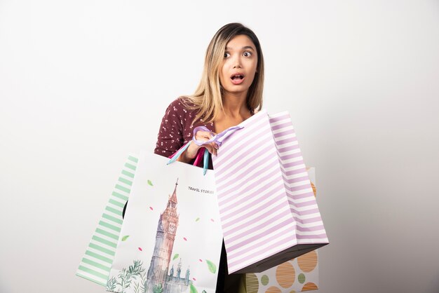 Free photo young woman holding shop bags on white wall.