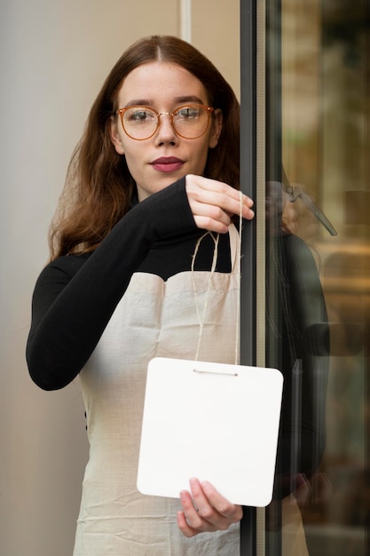 Young woman holding shop sign