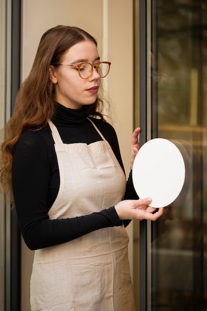 Free photo young woman holding shop sign