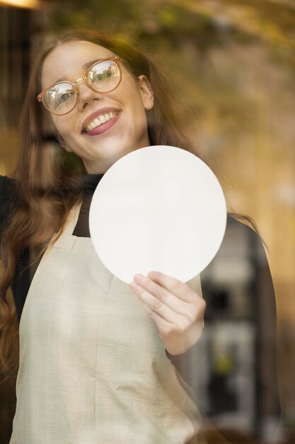 Young woman holding shop sign