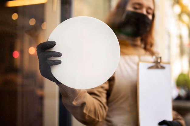 Young woman holding shop sign