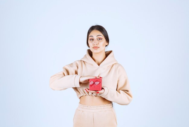 Young woman holding a small red gift box with both hands