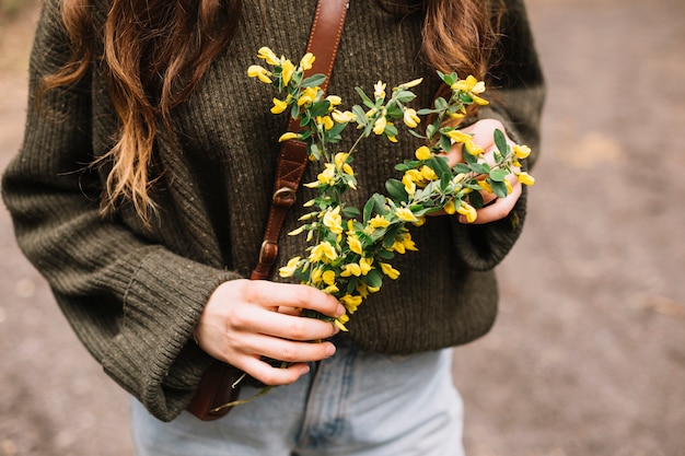 Foto gratuita giovane donna che tiene alcuni fiori selvatici