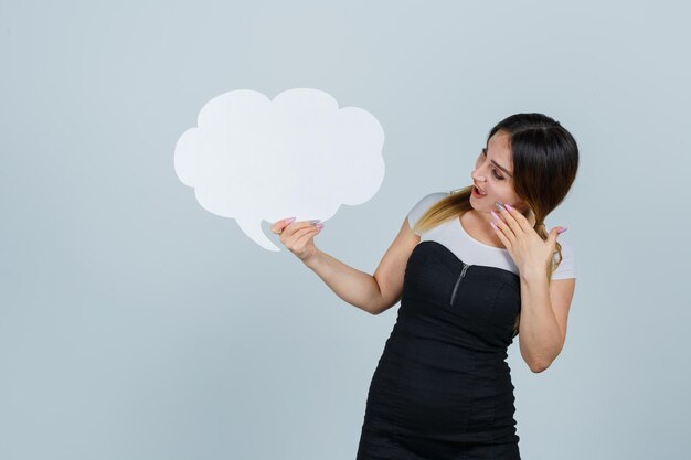 Young woman holding speech bubble and looking amazed