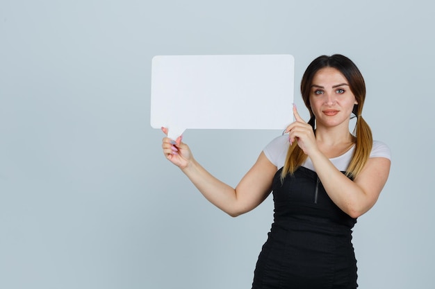 Young woman holding speech bubble and looking pleased