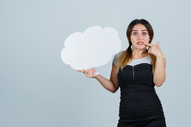 Free photo young woman holding speech bubble while biting her nails