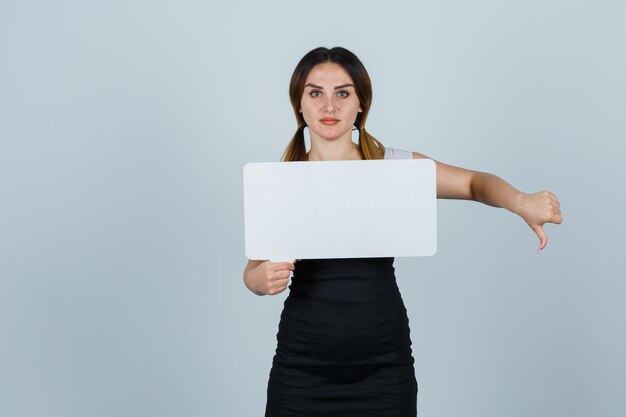 Young woman holding speech bubble while showing thumbs down