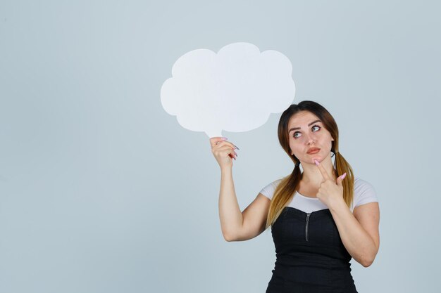 Young woman holding speech bubble while standing in thinking pose