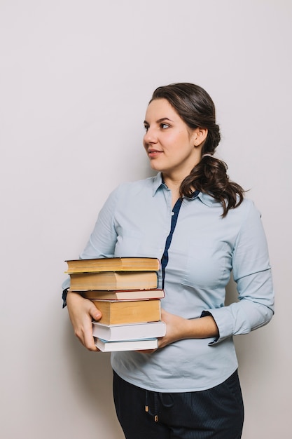 Young woman holding stack of books