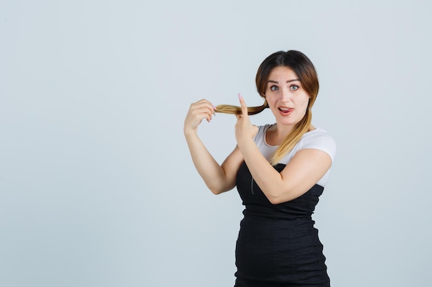 Young woman holding strand of hair and measuring length