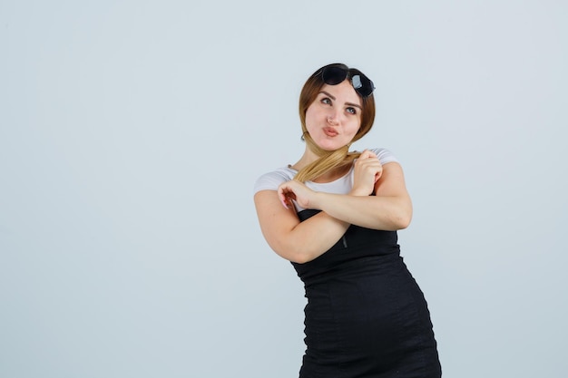 Foto gratuita giovane donna che tiene una ciocca di capelli mentre guarda lontano