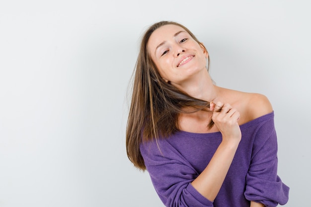 Free photo young woman holding strand while posing in violet shirt and looking cheerful. front view.