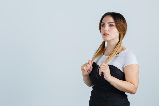 Young woman holding strands of hair while thinking about something