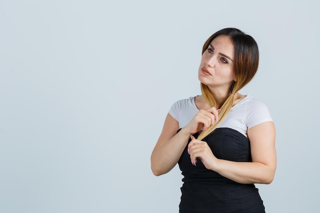 何かを考えながら髪の毛を保持している若い女性