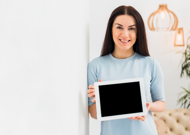 Foto gratuita compressa della tenuta della giovane donna con lo schermo nero in bianco