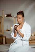 Foto gratuita tazza da tè della tenuta della giovane donna che si rilassa nel salone della stazione termale.