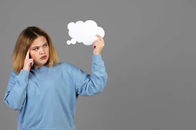 Free photo young woman holding a thought bubble with copy space
